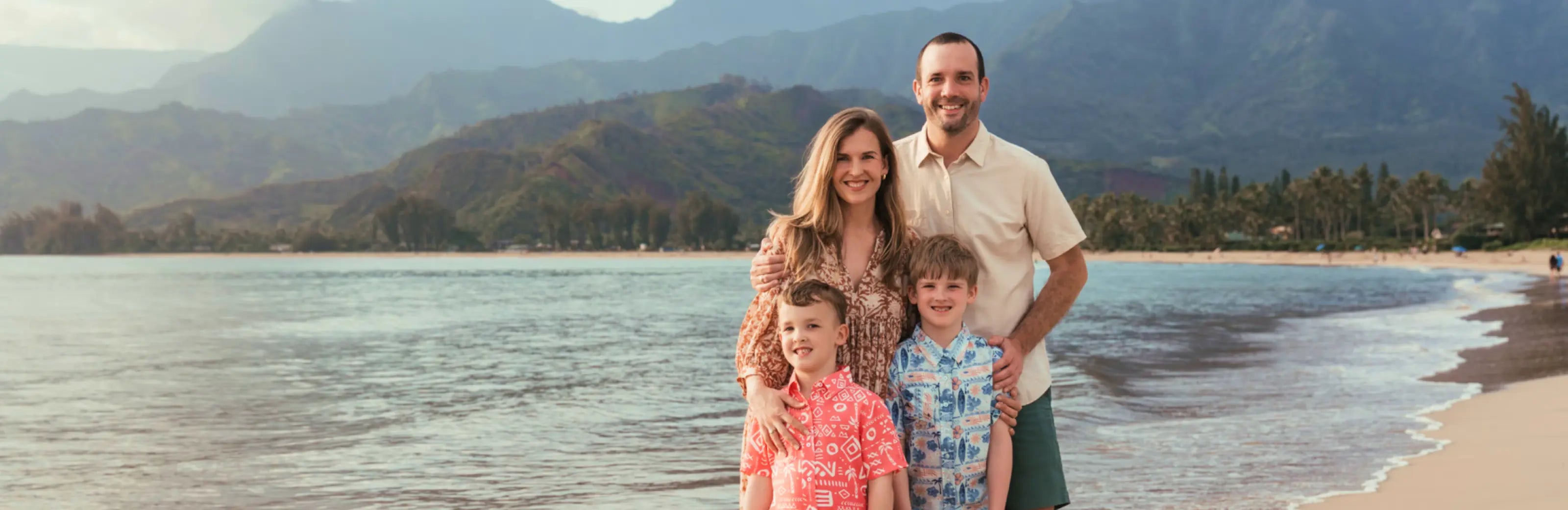 Bill and Malia posing with their sons on a beach in Hawaii.