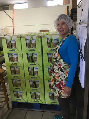 Becky posing next to a pallet of Anahola Granola bags.