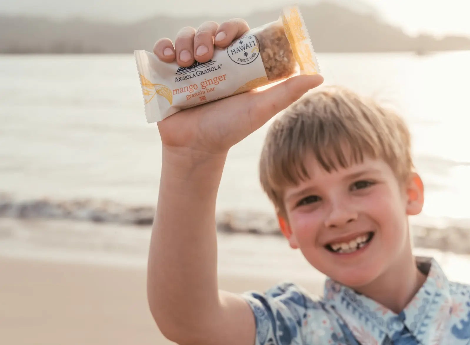 One of the children smiling and holding up a mango ginger granola bar.