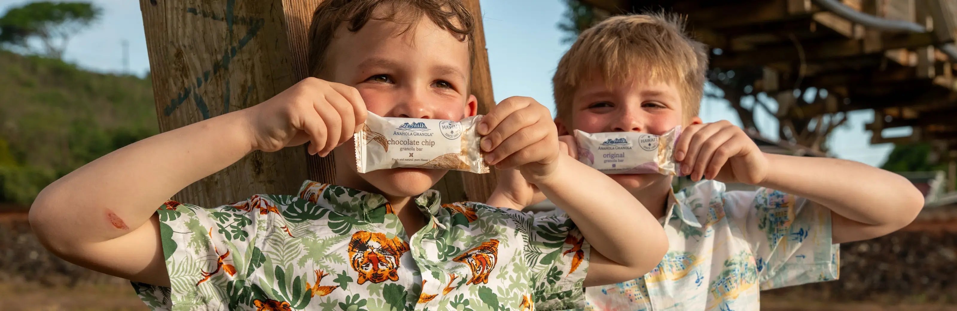 The boys holding up bars of granola outside.